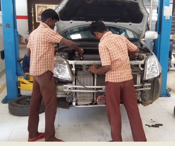 Students working on a vehicle on hydraulic lift